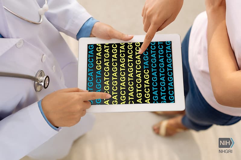 A clinician and patient reviewing a DNA sequence together on a tablet